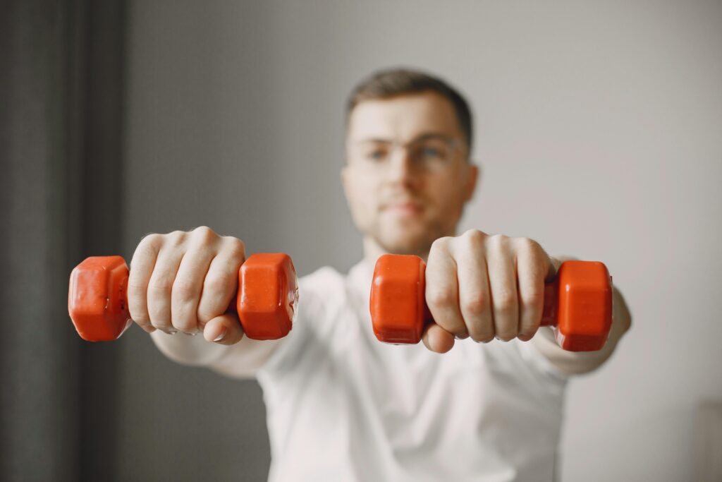 Mejores Mancuernas para Casa en Amazon 2026: Análisis y Guía de Compra Focused adult male exercising with red dumbbells at home, promoting a healthy lifestyle.