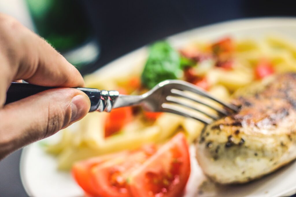 A vibrant close-up of a flavorful grilled chicken meal with pasta and veggies.