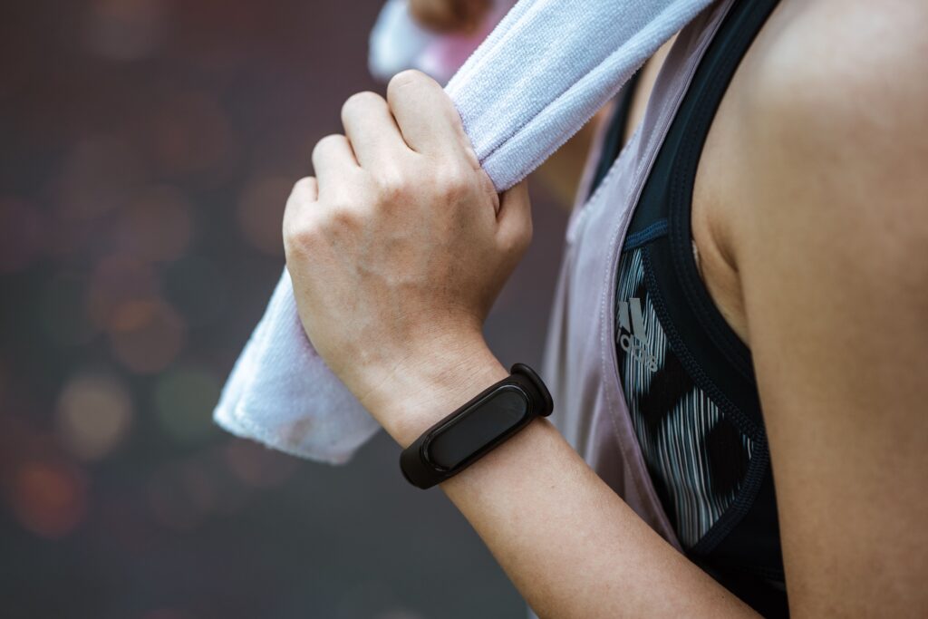 Mejores Pulseras de Actividad Fitness 2026: Comparativa de las 6 Mejores Marcas Side view of crop faceless female athlete in black smart watch and sports clothes holding cotton towel after practicing sport outdoors