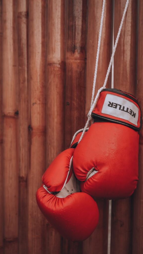 Guía Completa para Elegir Guantes de Boxeo: Onzas, Materiales y Tipos Explicados Striking red boxing gloves on a wooden background, symbolizing strength and determination.